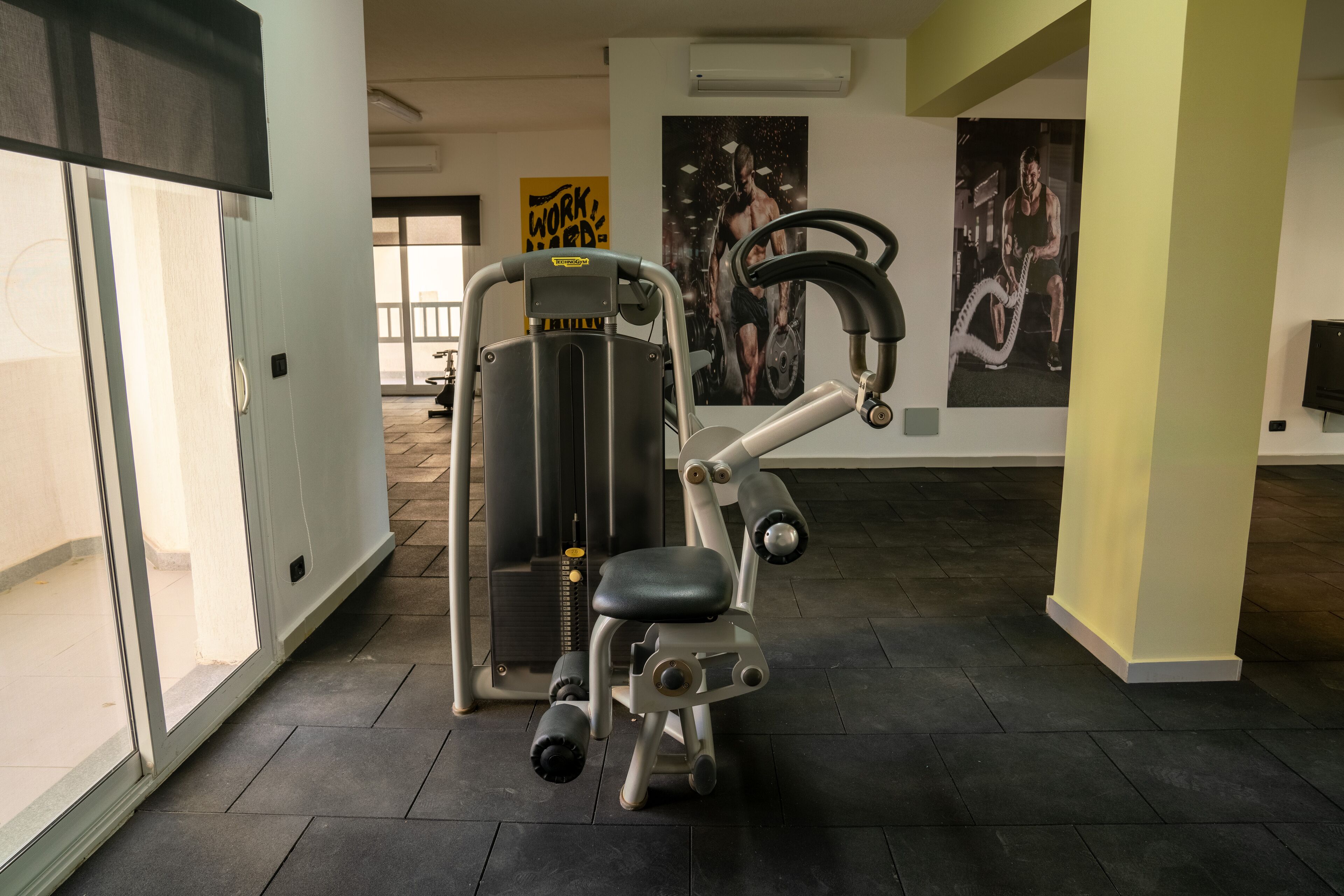 A gym with exercise equipment, a large mirror, and motivational posters on the walls.