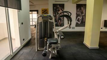 A gym with exercise equipment, a large mirror, and motivational posters on the walls.
