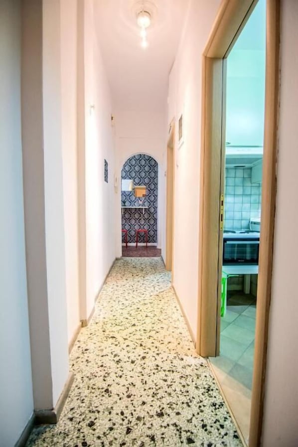 Enter a cozy space with a kitchenette and seating area, featuring a patterned floor and a light fixture above.