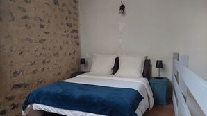 Een slaapkamer met een bed, twee nachtkastjes, een wandlamp en een witte balustrade.