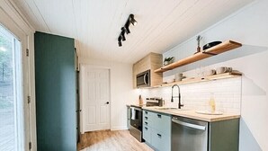 Eine moderne Küche mit Holzboden, integrierten Geräten und einem Fenster mit Blick auf einen Garten.