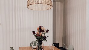 Ein Essbereich mit Holztisch, Stühlen, einem Blumenstrauß und einer Pendelleuchte.