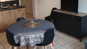 Un espace de vie compact comprenant un coin repas, une kitchenette et un téléviseur.