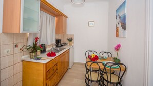 Eine kleine Küche mit Holzausstattung, einer weißen Arbeitsplatte und einem Essbereich mit Tisch und Stühlen.