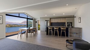 Une cuisine moderne dotée d’un grand îlot central, de tabourets de bar et offrant une vue sur un lac et des montagnes.