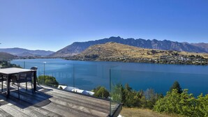 Une terrasse au bord du lac, avec une table et des chaises, d’où l’on peut admirer un lac paisible et des montagnes.