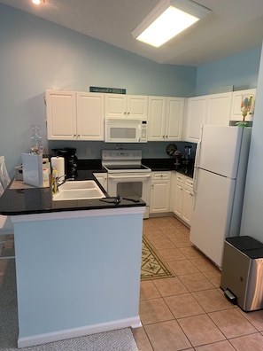 Enjoy cooking in this well-equipped kitchen with a central island, microwave, stove, refrigerator, coffee maker, and blender.