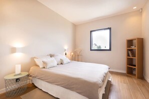Une chambre à coucher avec un lit, des lampes de chevet, une fenêtre et une bibliothèque en bois.