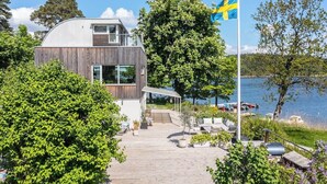 Una casa moderna con facciata in legno, un balcone e vista su un lago con barche.