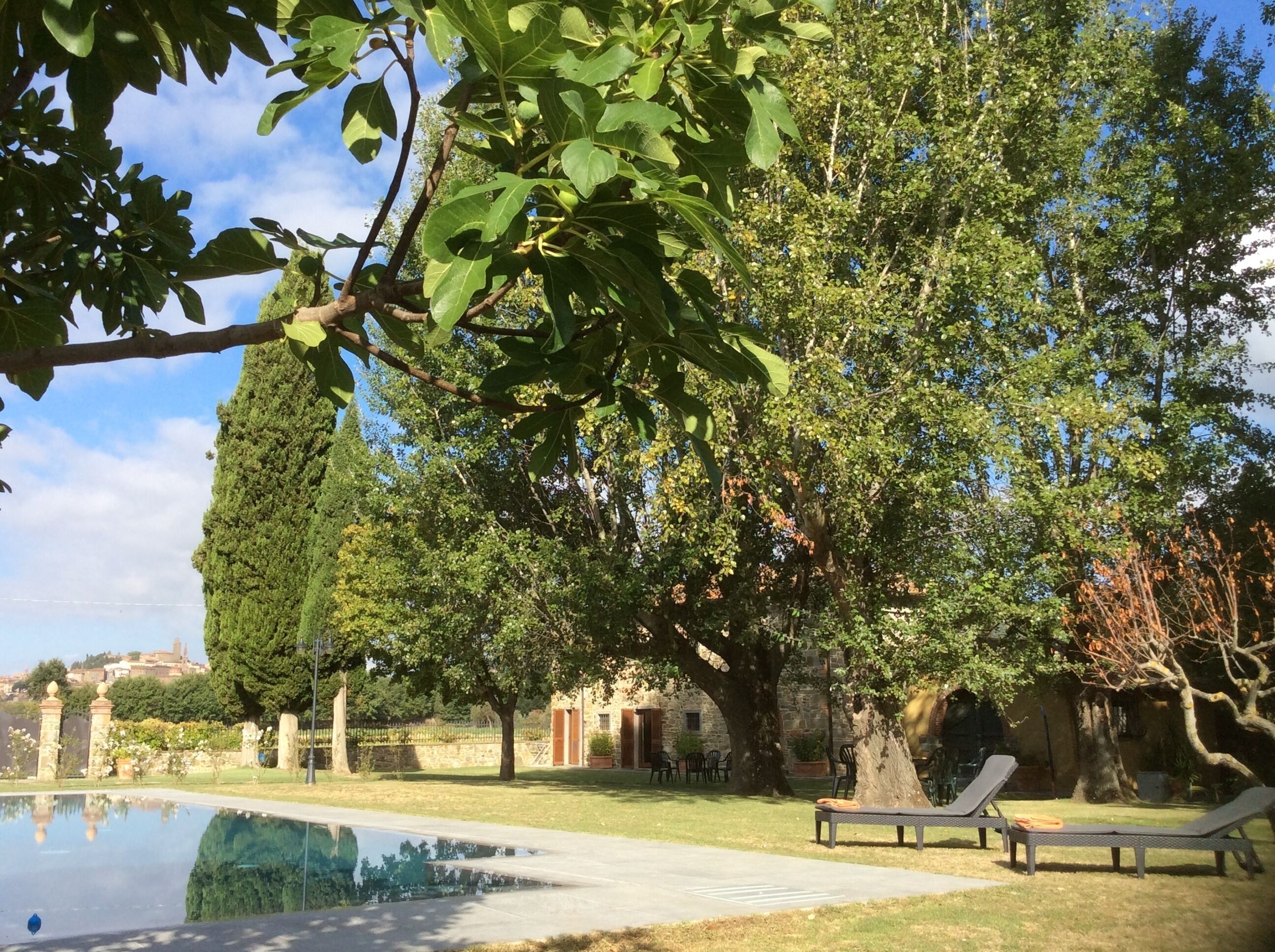 Un espace extérieur paisible avec une piscine, des chaises longues et un bâtiment en pierre agrémenté d’un jardin.