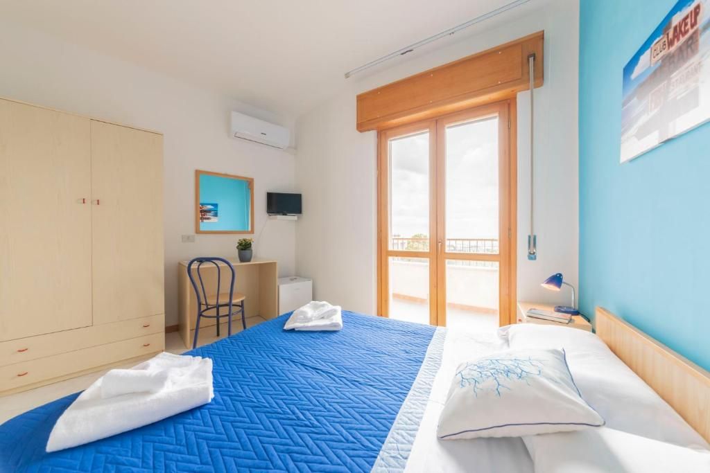 Ein Hotelzimmer mit Bett, Schreibtisch, Stuhl, Kleiderschrank und einem Balkon.
