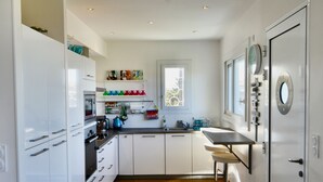 Une cuisine moderne avec des meubles blancs, un plancher en bois et un tabouret de bar.