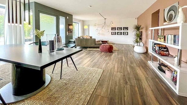A modern living room with a dining table, sofa, bookshelf, and decorative wall art. - Ferienbungalow Iwele (Marktbreit)
