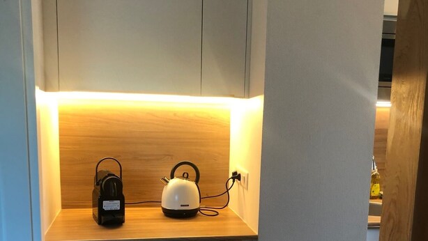 A compact kitchen with a built-in oven and a countertop with a kettle and a bottle. - Appartement Indépendant - Wifi - Parking- Petit Déjeuner (Ittenheim)