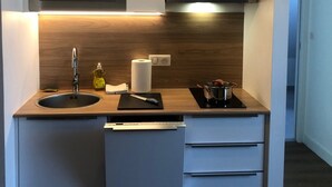A modern kitchen with a built-in microwave, a sink, a stove, and a hanging light fixture. - Appartement Indépendant - Wifi - Parking- Petit Déjeuner (Ittenheim)