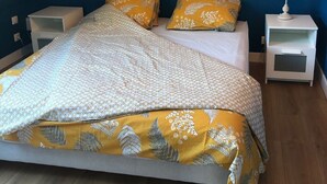 A bedroom with a bed, two nightstands, a lamp, and a blue wall. - Appartement Indépendant - Wifi - Parking- Petit Déjeuner (Ittenheim)