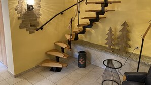 Una escalera de caracol con acabado de madera, una lámpara de pared y un adorno mural.