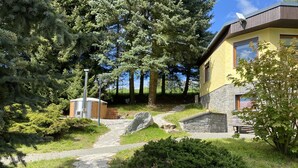 Un sendero de piedra que lleva a una casa con zócalo de piedra y fachada amarilla.