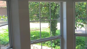 Una habitación con ventanas amplias, suelo de madera y vistas a zonas verdes.