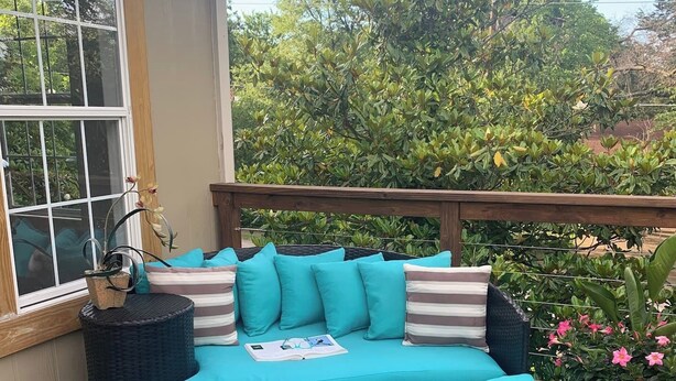 Un espacio de asiento al aire libre circular, con cojines color turquesa y un libro encima.