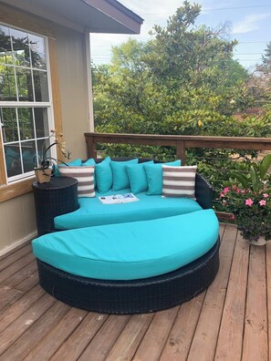 A round outdoor seating area with teal cushions and a book on it.