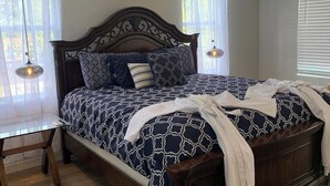 Un dormitorio con una cama de madera, una mesita de vidrio y un ventilador de techo.