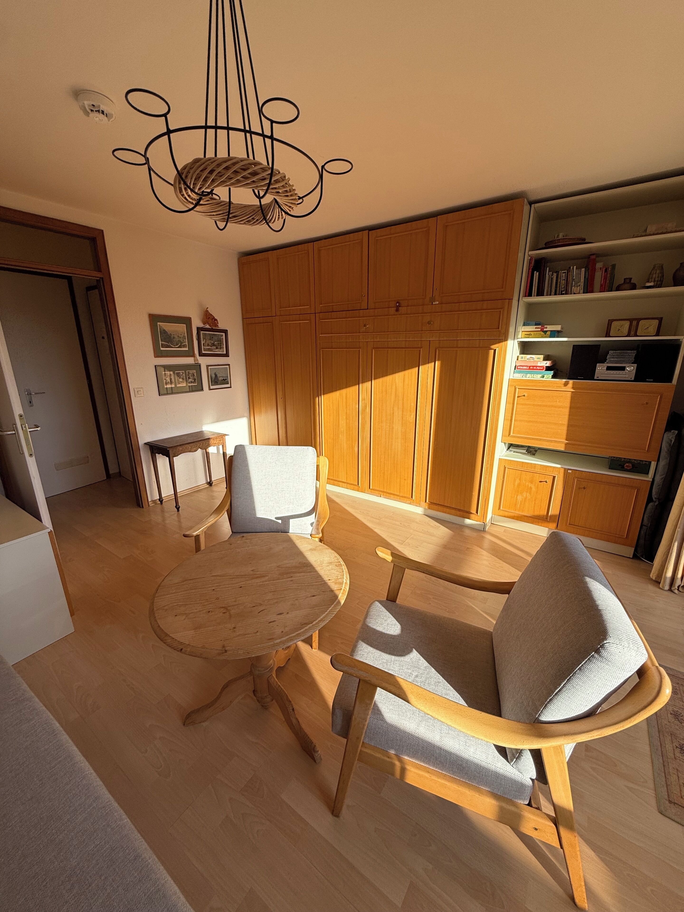 Une pièce comprenant une table et des chaises en bois, une bibliothèque et une grande armoire en bois.