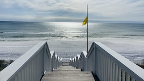 A wooden boardwalk leading to a beach with a flag on a pole. - Gorgeous Listing in Seaside Proper with Beautiful Unobstructed Gulf Views (Santa Rosa Beach)