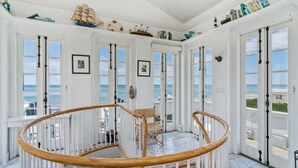 A spacious room with a wooden spiral staircase, large windows with ocean views, and nautical decor. - Gorgeous Listing in Seaside Proper with Beautiful Unobstructed Gulf Views (Santa Rosa Beach)