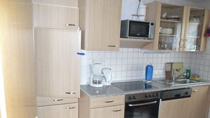 Una cocina compacta con muebles de madera, microondas, cafetera y lavavajillas.