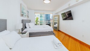 A hotel room with a bed, a desk, a chair, a TV, and a window with a city view. - Amazing 2BR APT @Brickell, Free Parking (Miami)