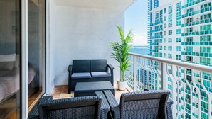 A balcony with wicker furniture, a potted plant, and a view of high-rise buildings. - Amazing 2BR APT @Brickell, Free Parking (Miami)