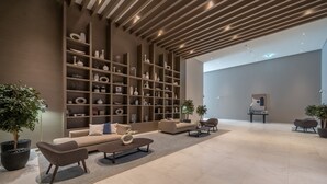 Un vestíbulo amplio con diseño moderno, que presenta una gran estantería, asientos cómodos y plantas en macetas.
