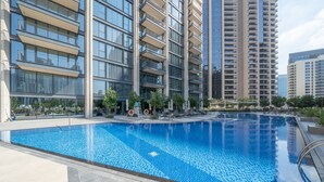 Un moderno edificio de apartamentos con piscina, mobiliario exterior y un jardín bien cuidado.