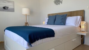 A neatly made bed with a blue throw blanket, a bedside lamp, and a wall-mounted fish decoration. - Just 5 Steps to the Beach · Stylish Whole House · AC · Terrace & BBQ · WIFI (Cunit)