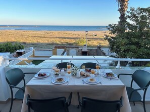Une table à manger dress ée avec des assiettes, des verres, et une vue sur la plage.