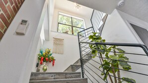Escada com acabamento em madeira, corrimão de metal e luminária fixada na parede.