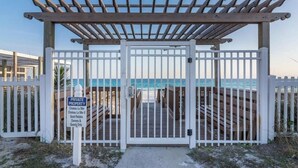 A gated entrance to a private property with a wooden deck and a view of the ocean. - 300 Steps to the Emerald Beach (Destin)