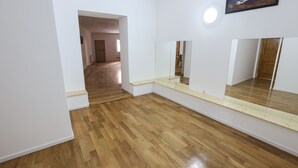 Une pièce avec un plancher en bois, des murs blancs et un grand miroir.