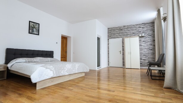 Une chambre à coucher comprenant un lit, une armoire, une chaise et une porte donnant sur une autre pièce.