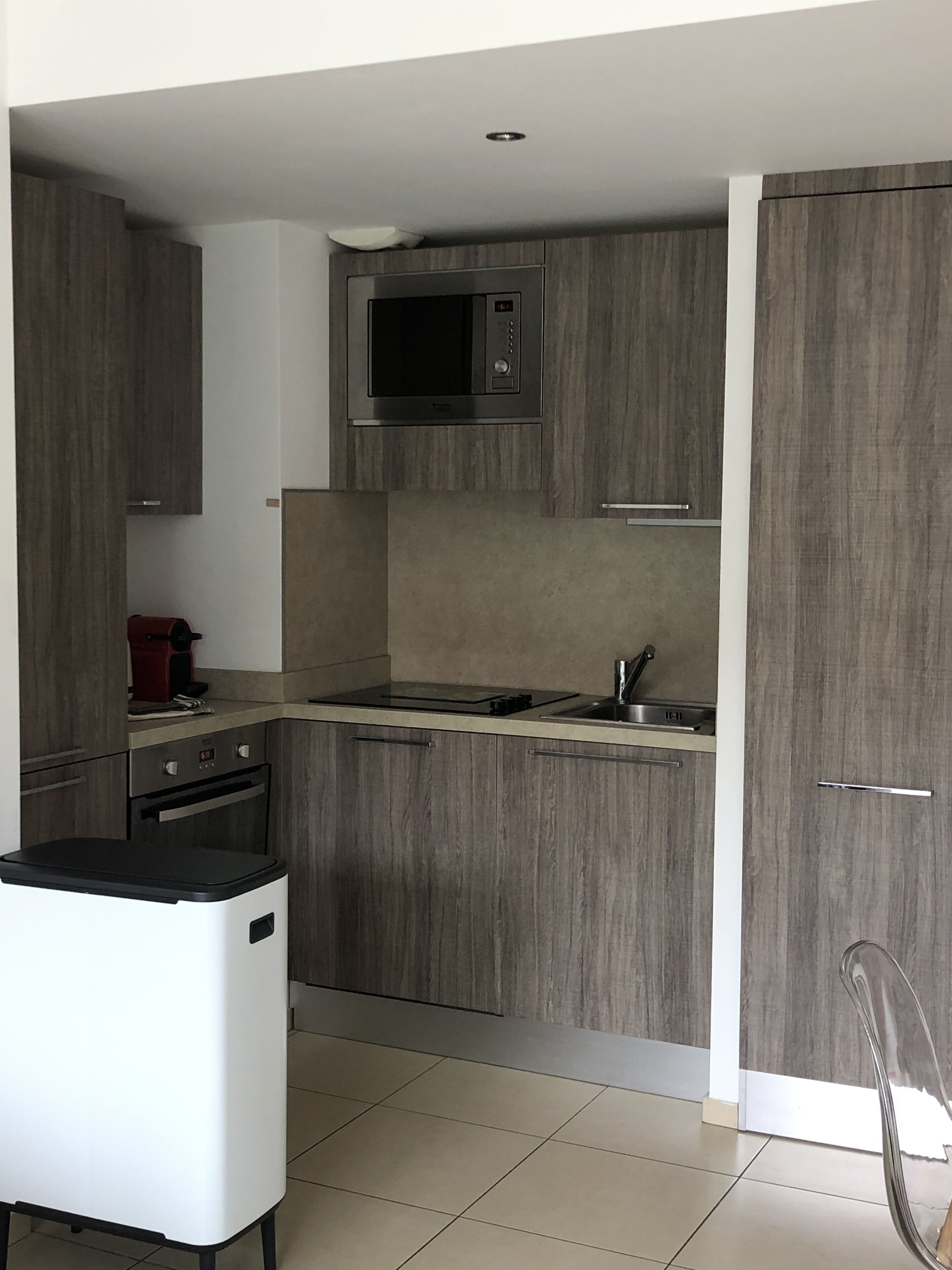 A modern kitchen with grey cabinets, a stainless steel microwave, and a built-in oven.