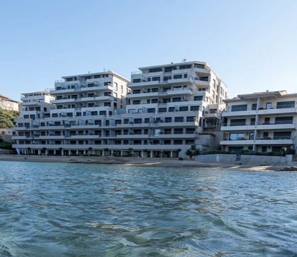 A multi-story building with balconies, located near a body of water.