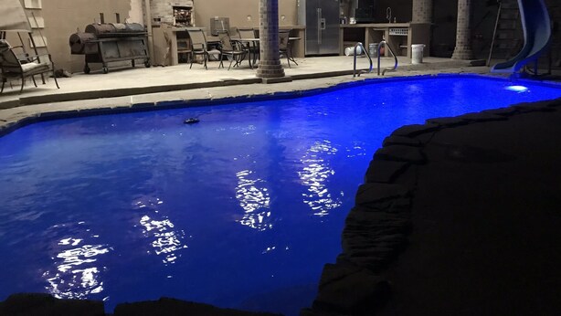A swimming pool with a stone edge, a barbecue area, and outdoor seating.