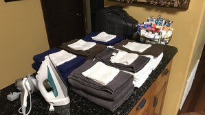 A kitchen counter with a coffee maker, iron, and towels.