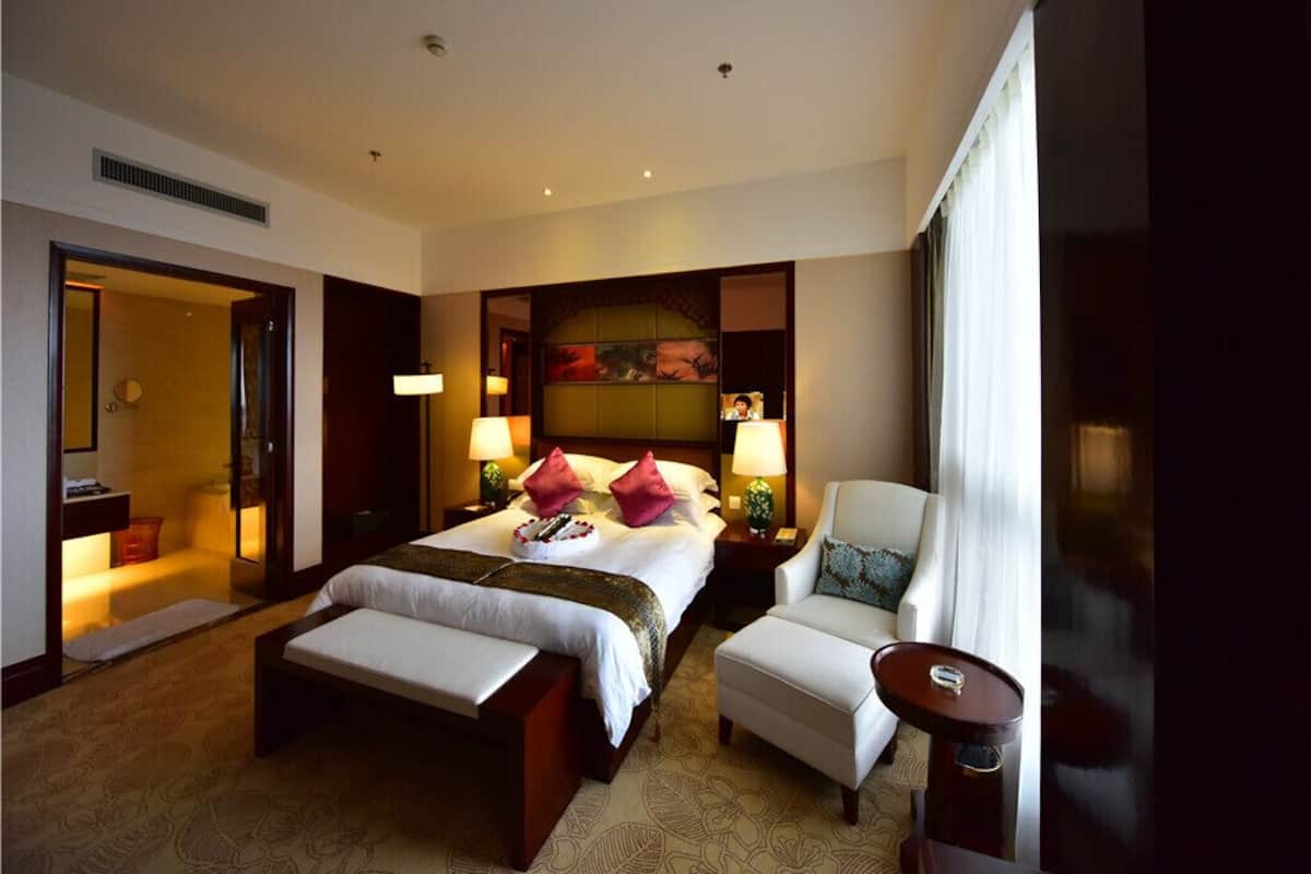 A hotel room with a large bed, two bedside tables with lamps, a chair, and a small table.