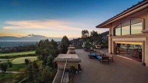Um pátio espaçoso ao ar livre com vista para um campo de golfe e montanhas distantes.