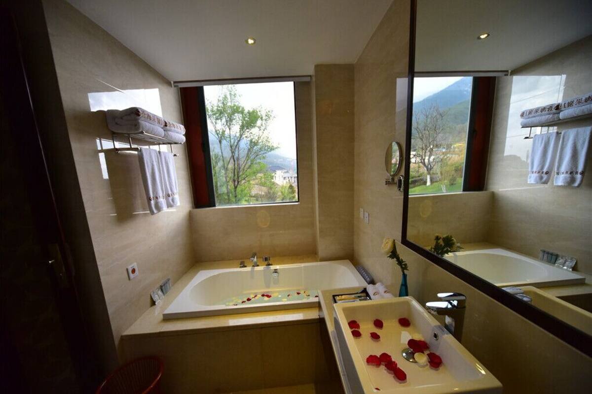 A modern bathroom with two sinks, a large mirror, and a view of a mountainous landscape through the windows.
