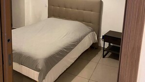 Een slaapkamer met een bed, een nachtkastje en een hanglamp.