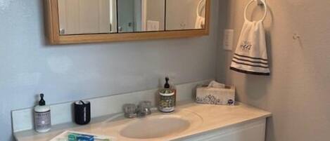 A bathroom with a large mirror, white vanity, and a red carpet.