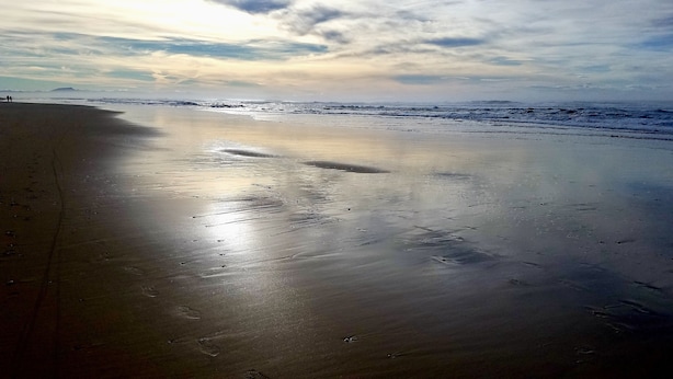 A beach with wet sand and footprints, a cloudy sky, and distant mountains. - Soustons Grande Propriété Dans un Écrin de Verdure en Lisière de Forêt (Soustons)